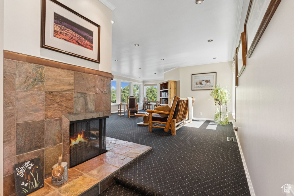 Carpeted living area with a tile fireplace, recessed lighting, and crown molding