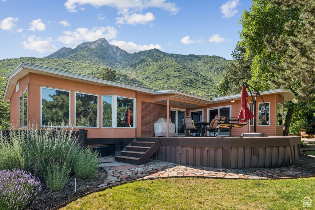 Back of house with a mountain view and a lawn
