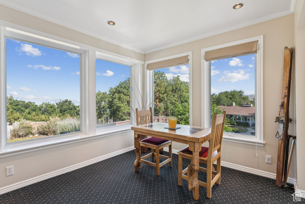 Dining area featuring dark colored carpet, ornamental molding, and recessed lighting