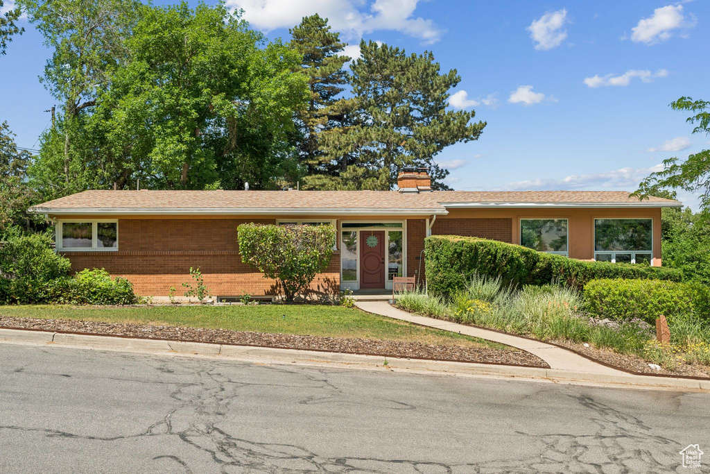 Ranch-style home featuring brick siding and a chimney