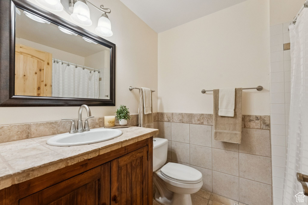 Full bathroom with tile walls, vanity, a wainscoted wall, a shower with shower curtain, and tile patterned flooring