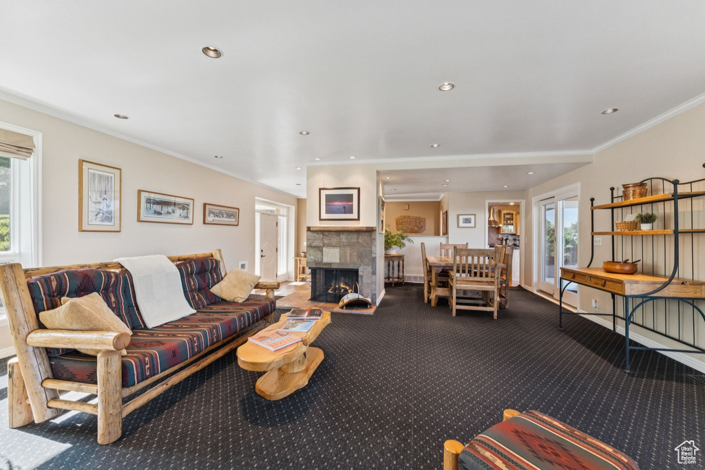 Carpeted living area with healthy amount of natural light, a lit fireplace, crown molding, and recessed lighting