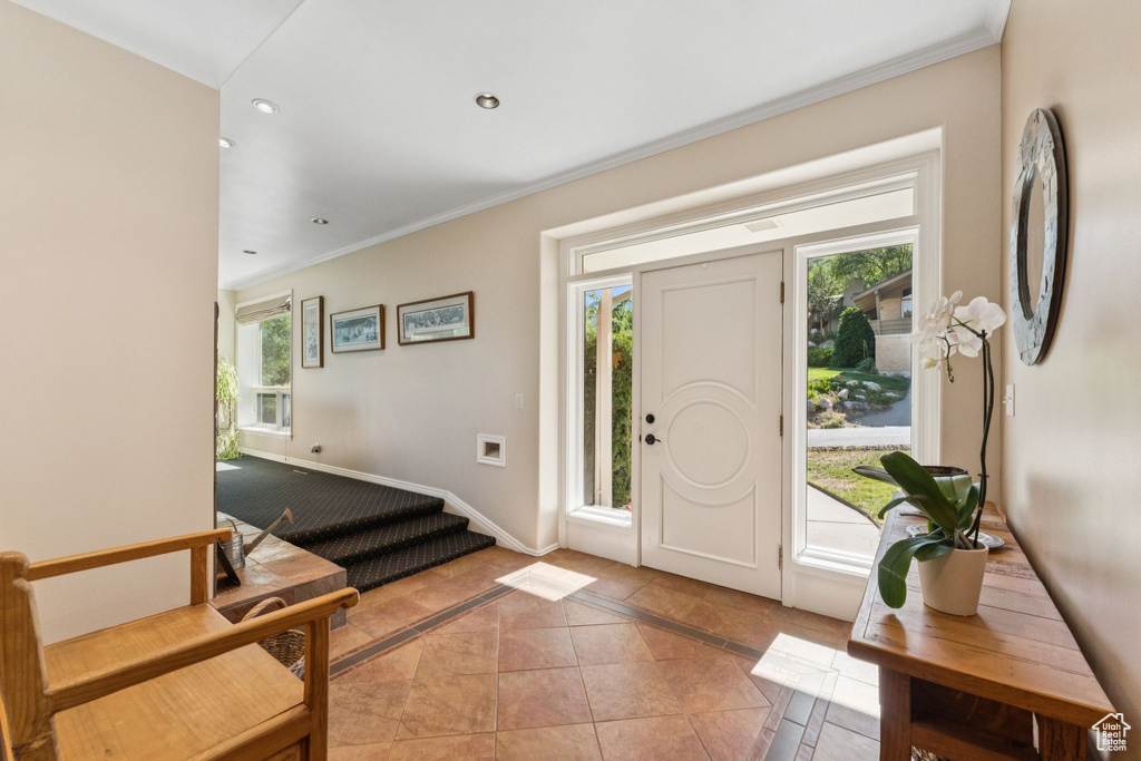 Foyer with inlaid floor details, healthy amount of natural light, crown molding, recessed lighting, and light tile patterned floors