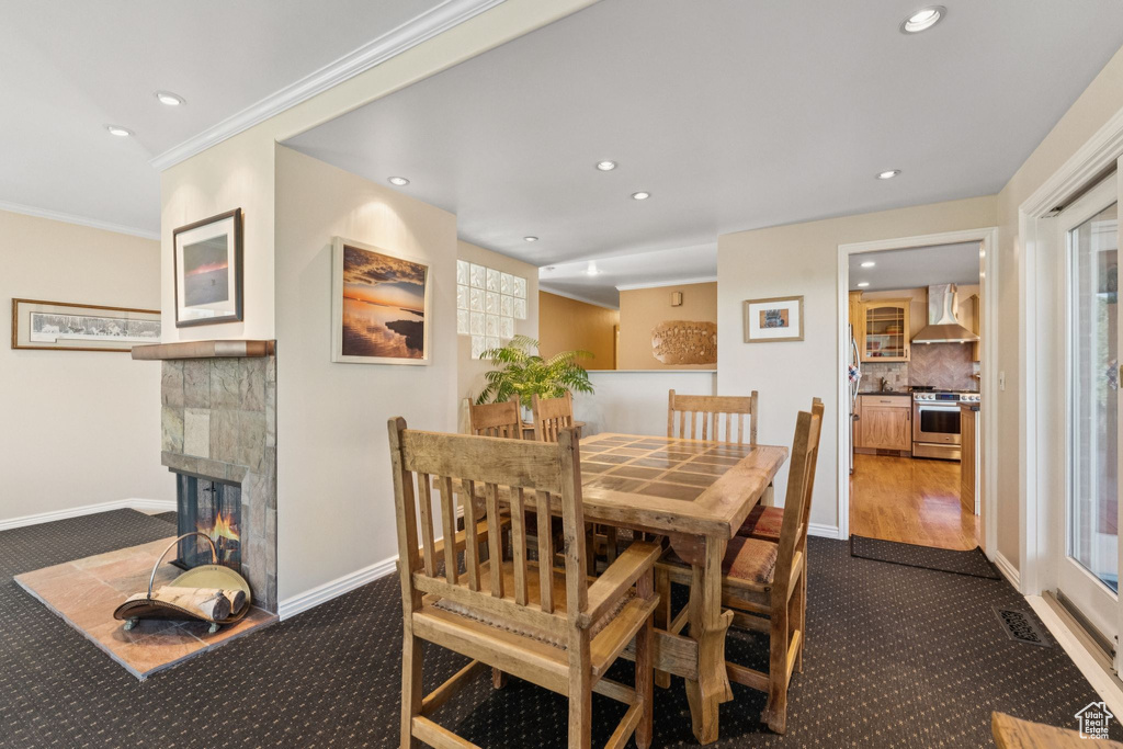 Dining space featuring dark carpet, recessed lighting, crown molding, and a fireplace