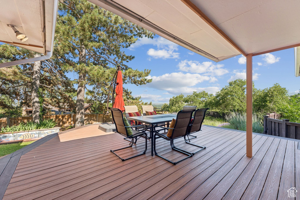 Wooden deck with outdoor dining area and a fenced backyard