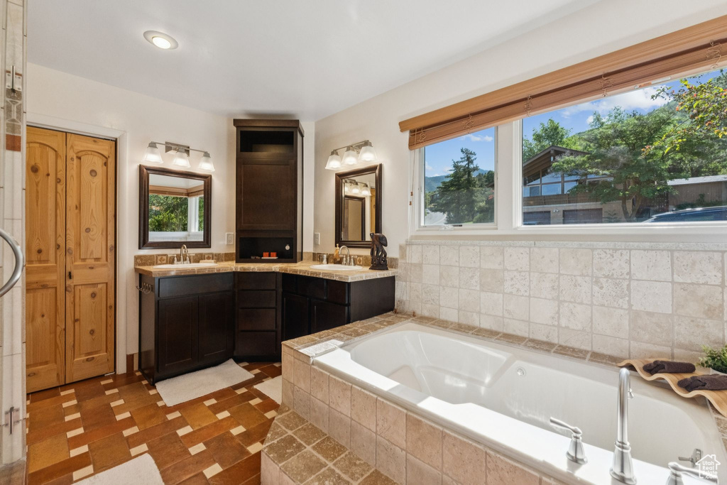 Bathroom featuring double vanity, a garden tub, and plenty of natural light