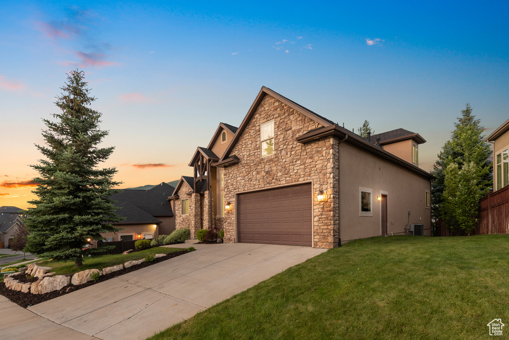 Traditional home featuring stone siding, concrete driveway, a garage, and stucco siding