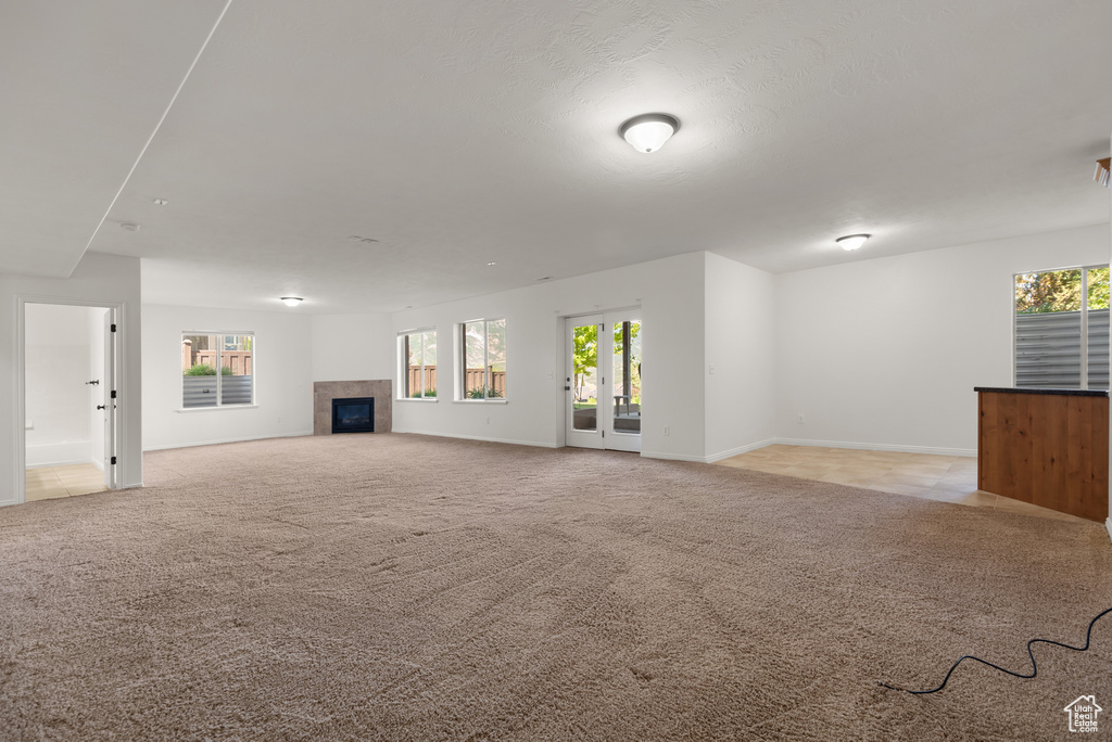Unfurnished living room with a tiled fireplace and light carpet