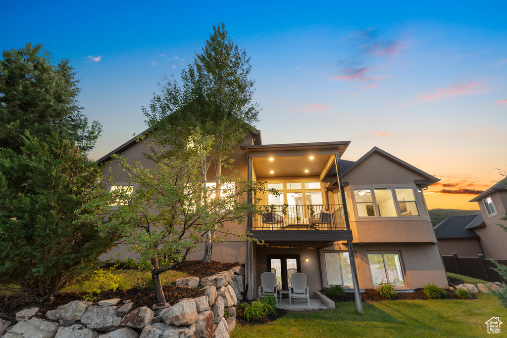 Back of house featuring stucco siding, a patio area, and a lawn