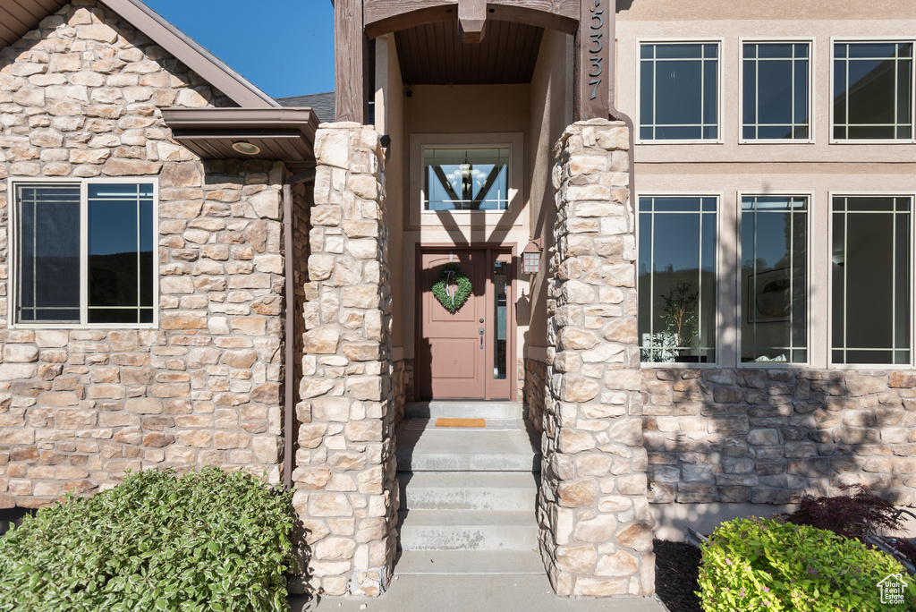 Doorway to property featuring stone siding and stucco siding