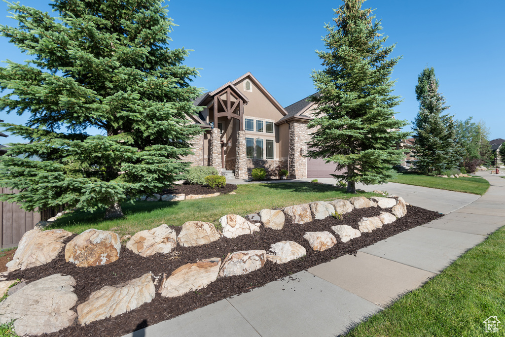 View of front facade featuring stone siding, stucco siding, and driveway