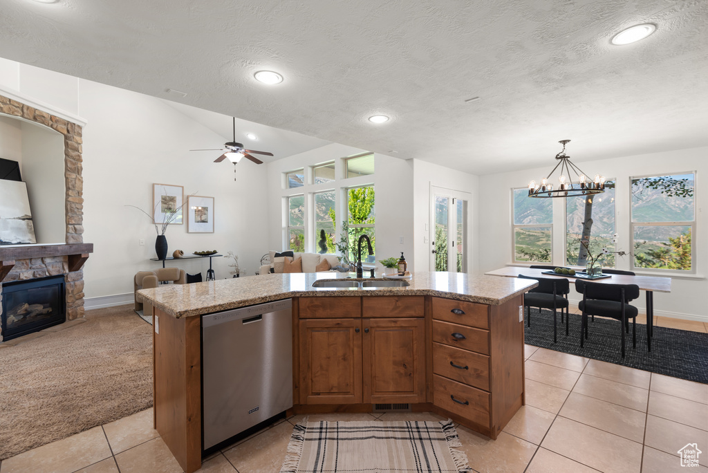Kitchen with dishwasher, open floor plan, a stone fireplace, healthy amount of natural light, and a textured ceiling