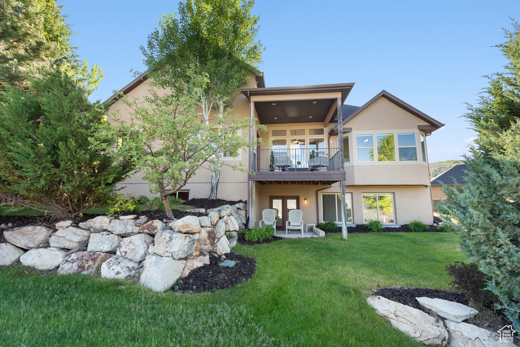 Back of property with stucco siding, a yard, french doors, a patio, and a balcony