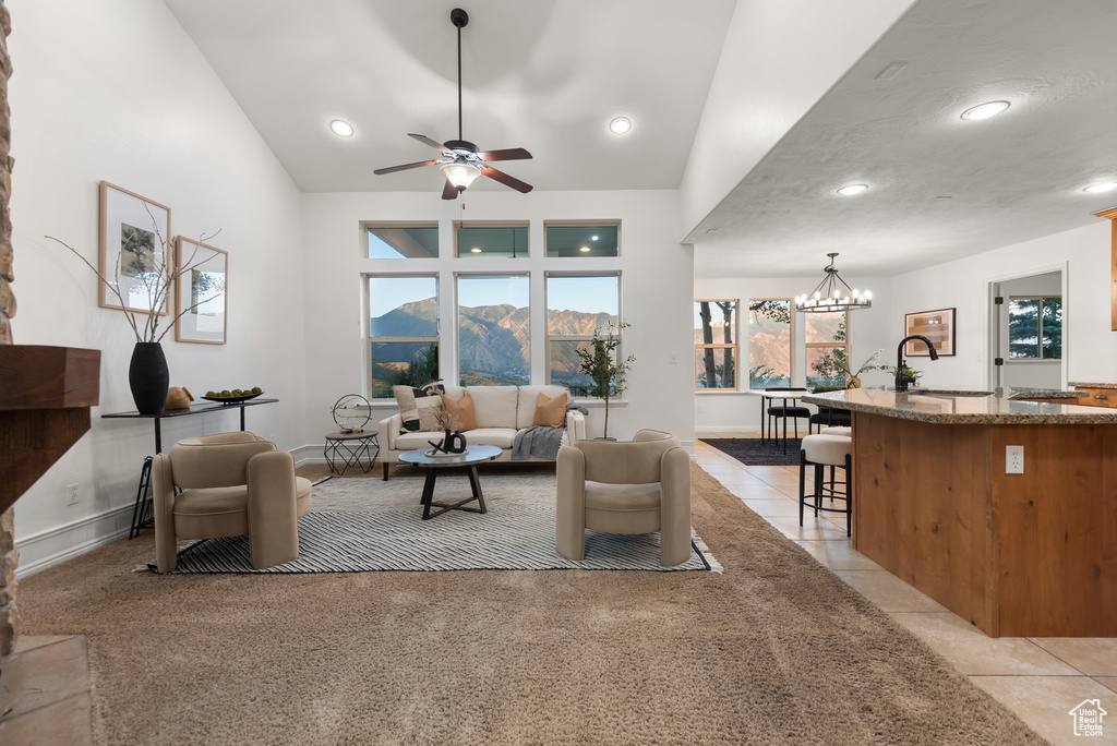Living room featuring a chandelier, ceiling fan, vaulted ceiling, light tile patterned floors, and recessed lighting