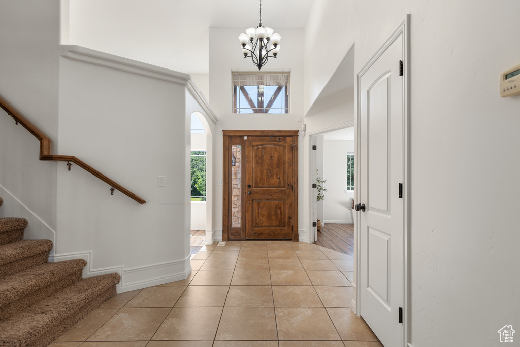 Entrance foyer featuring a chandelier, light tile patterned floors, stairs, and a high ceiling
