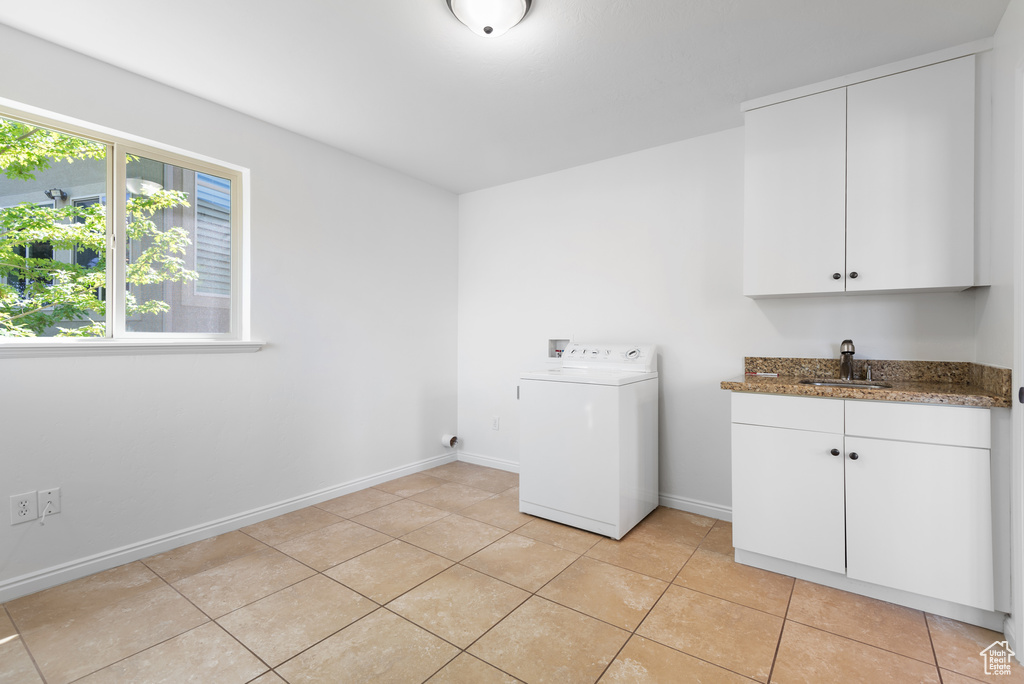 Laundry area with washer / clothes dryer, bar with sink, light tile patterned flooring, and cabinet space