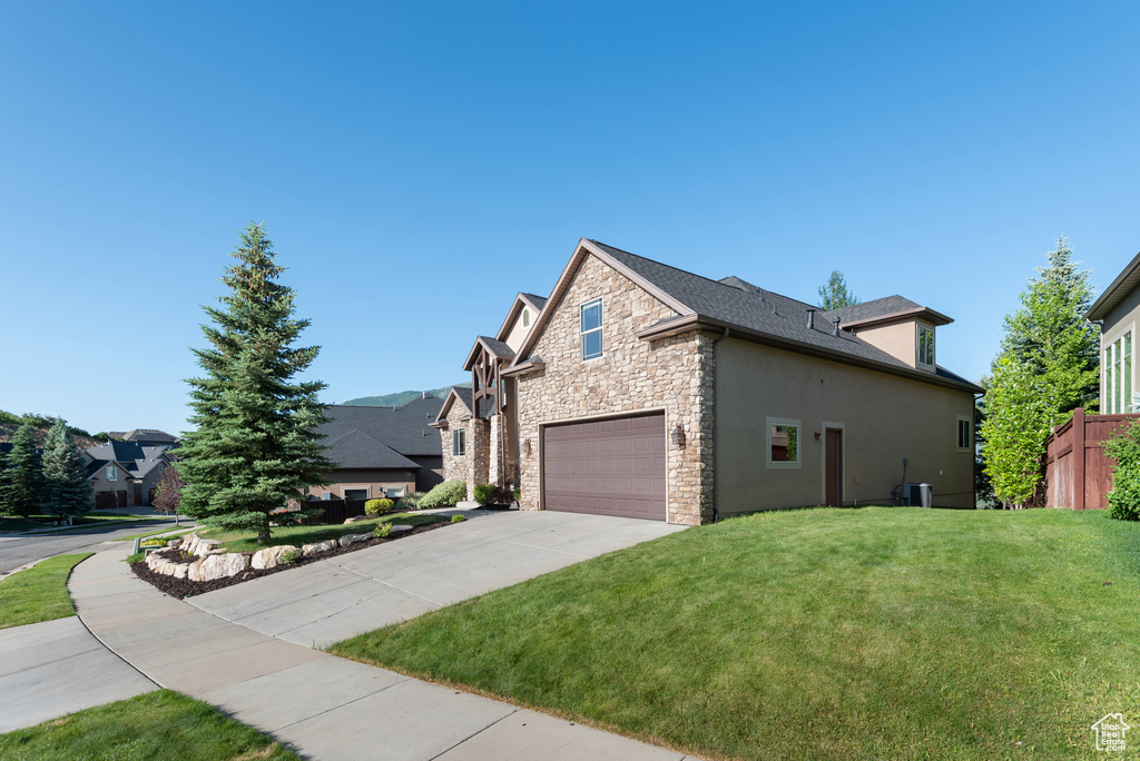 View of side of home featuring stone siding, concrete driveway, stucco siding, and a garage