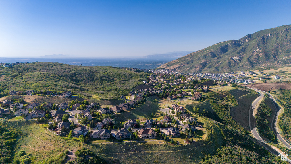 Aerial view of property and surrounding area featuring mountains and nearby suburban area