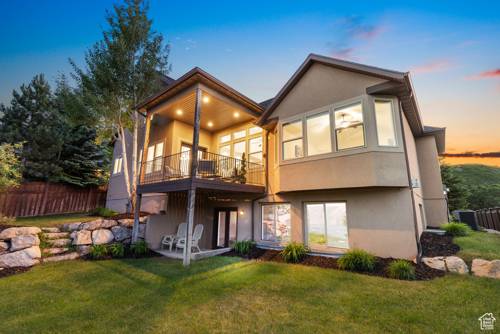 Back of property at dusk with a balcony and stucco siding
