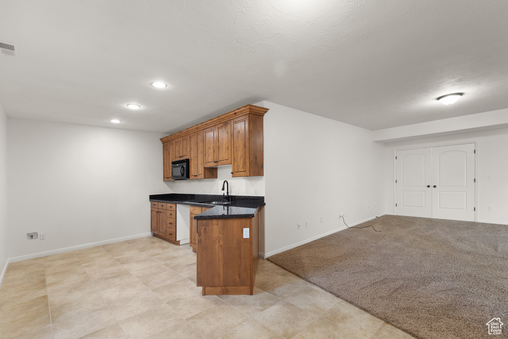 Kitchen featuring black microwave, brown cabinetry, and recessed lighting
