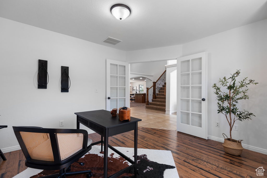 Office area featuring french doors, arched walkways, and wood finished floors