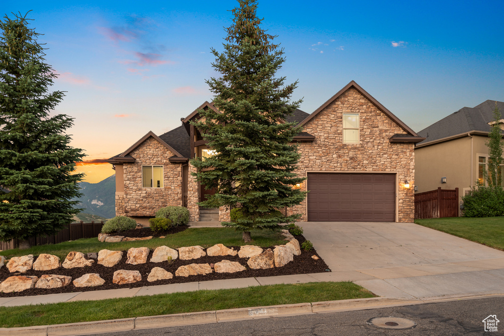 View of front of home featuring stone siding, a garage, and concrete driveway
