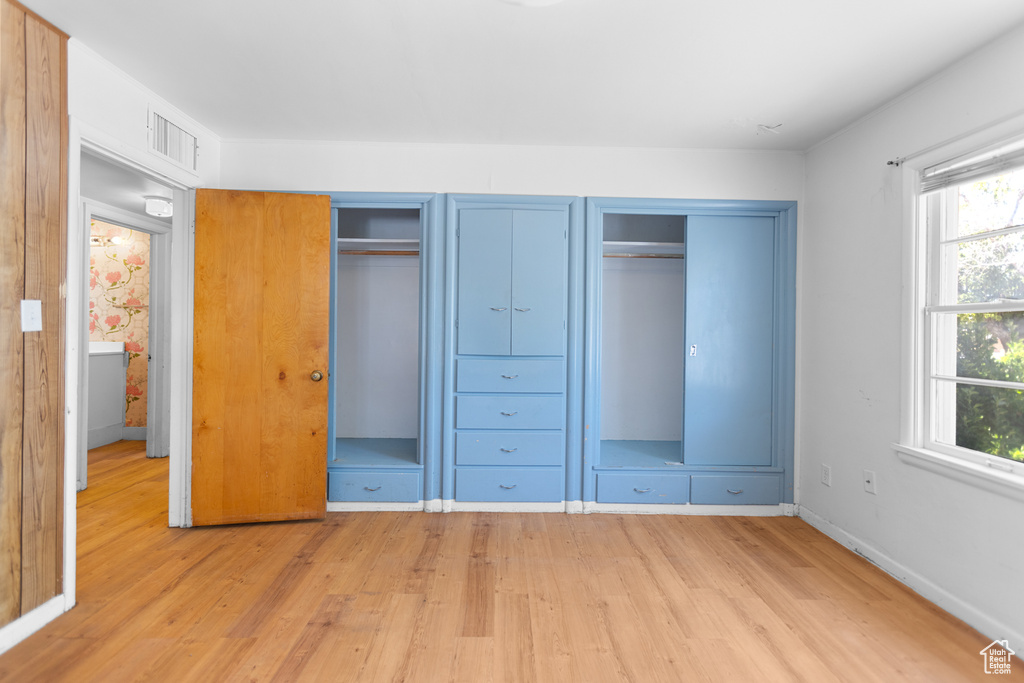 Unfurnished bedroom with light wood finished floors, two closets, and multiple windows