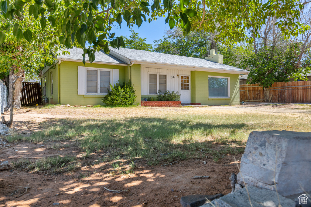 Single story home featuring a chimney, concrete block siding, and a shingled roof