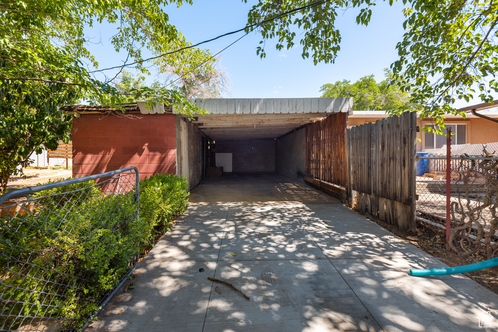 View of parking / parking lot with concrete driveway and an attached carport