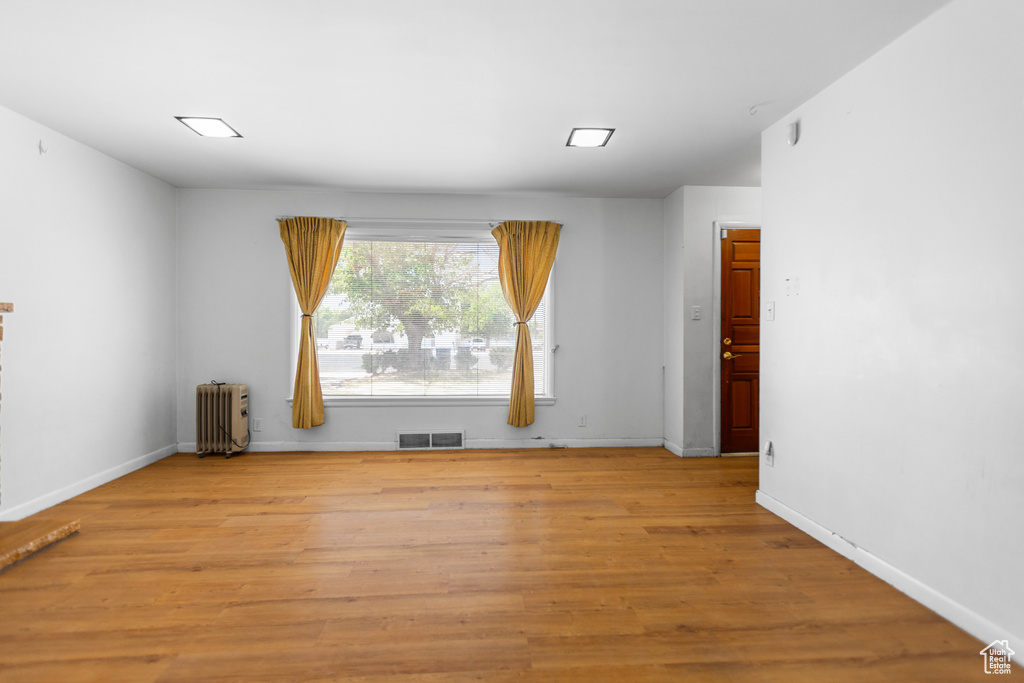 Empty room with radiator heating unit and light wood-type flooring