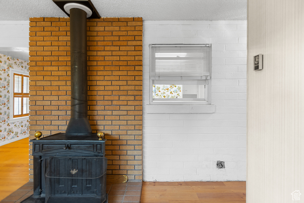 Detailed view of a wood stove, wood finished floors, and a textured ceiling