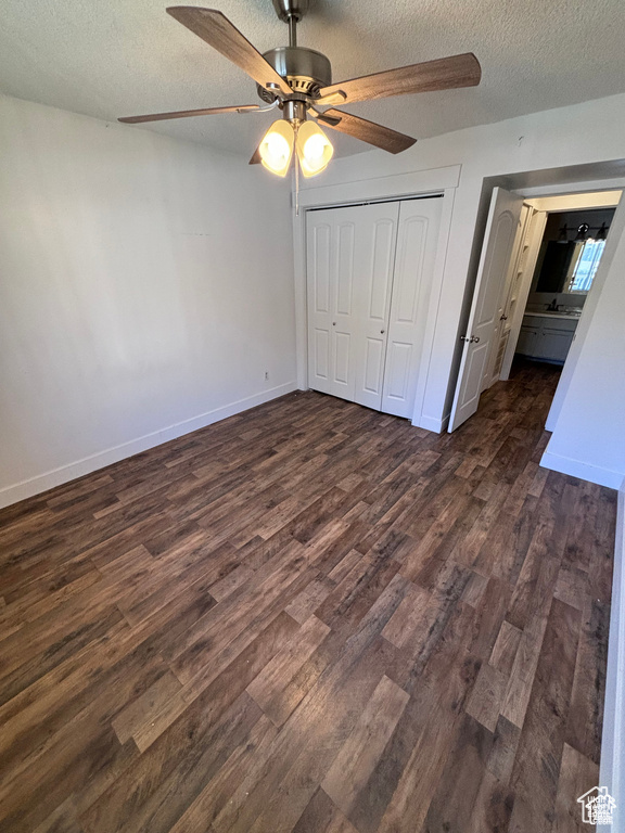 Unfurnished bedroom featuring a textured ceiling, dark wood-style flooring, a closet, and ceiling fan