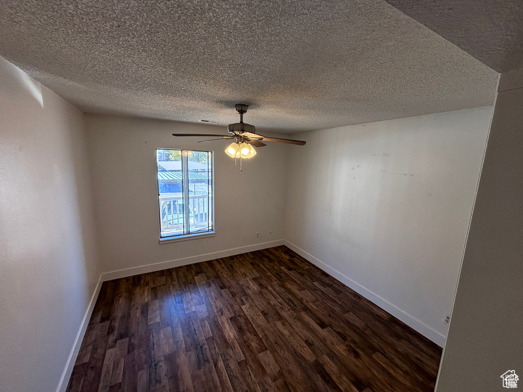 Spare room with dark wood finished floors, a textured ceiling, and ceiling fan
