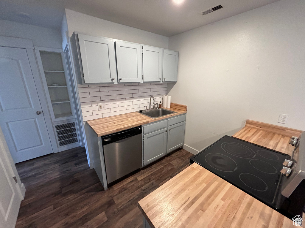 Kitchen featuring dishwasher, range with electric cooktop, butcher block counters, backsplash, and dark wood finished floors