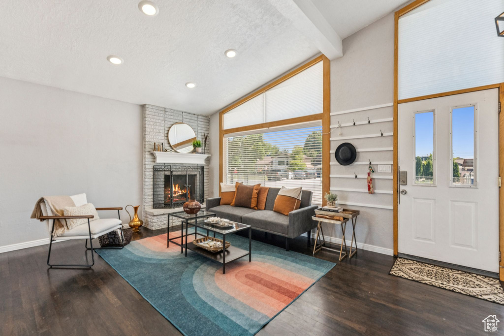 Living area with wood finished floors, a fireplace, beam ceiling, recessed lighting, and a textured ceiling