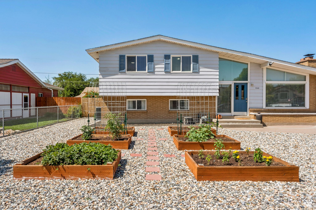 View of front of house featuring a garden, brick siding, and a chimney