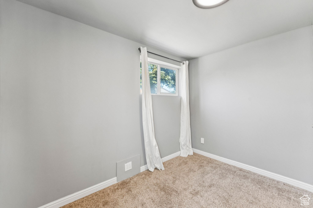 Empty room featuring light colored carpet and baseboards