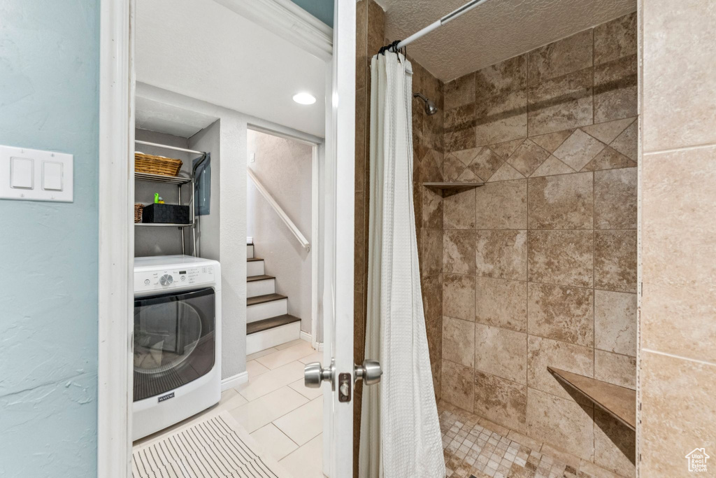 Full bath featuring washer / clothes dryer, a tile shower, and tile patterned floors