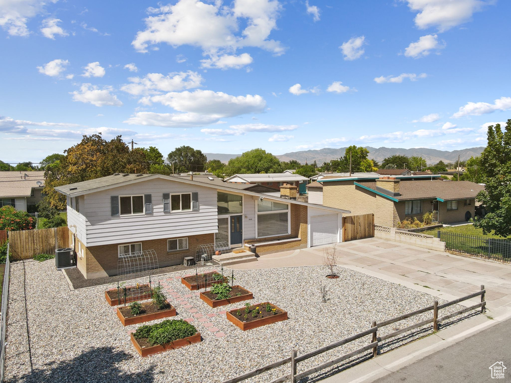 View of front of home with concrete driveway, a vegetable garden, a mountain view, and a garage