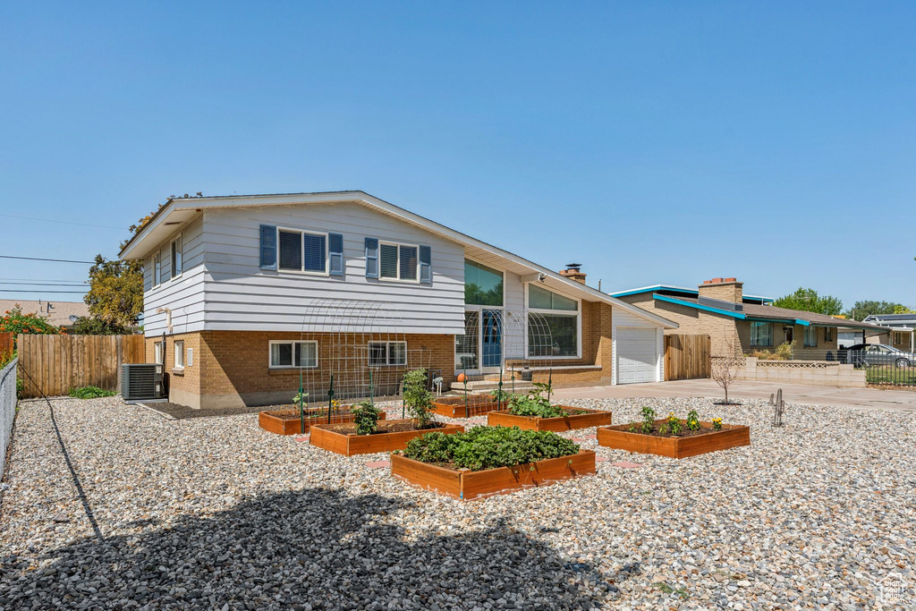 Back of house featuring a garden, driveway, and brick siding