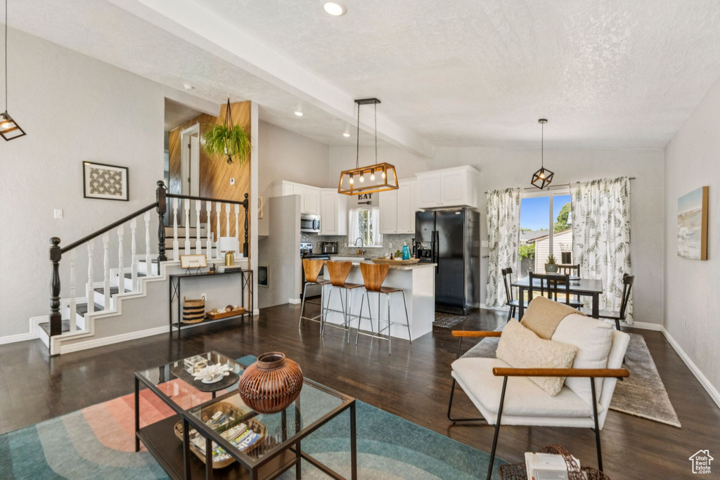 Living room featuring dark wood-type flooring, stairway, a textured ceiling, and recessed lighting