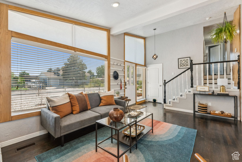 Living room with stairway, beamed ceiling, wood finished floors, and a towering ceiling