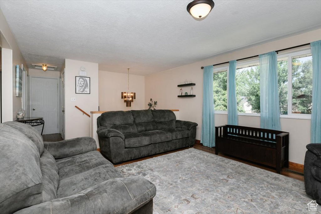 Living room with a chandelier, wood finished floors, and a textured ceiling