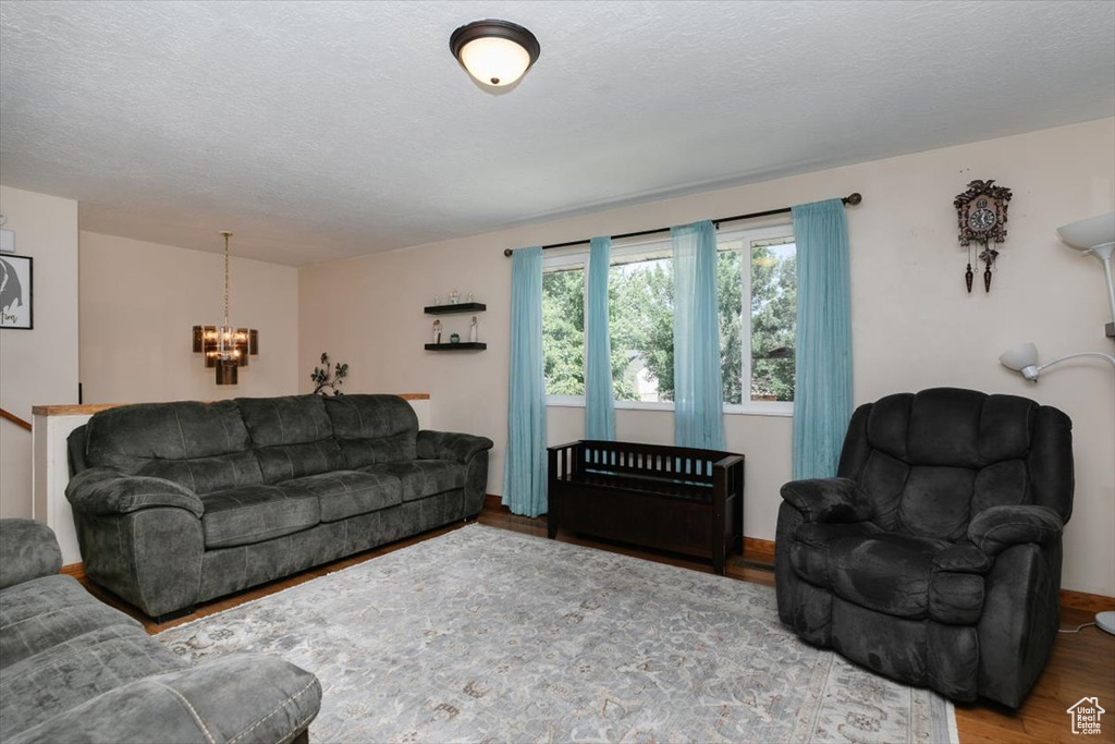 Living area with a chandelier, wood finished floors, and a textured ceiling