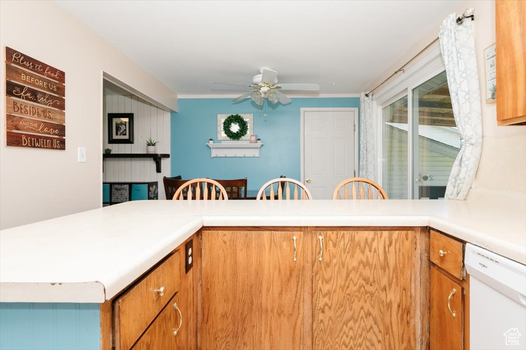 Kitchen featuring white dishwasher, ceiling fan, light countertops, and brown cabinetry
