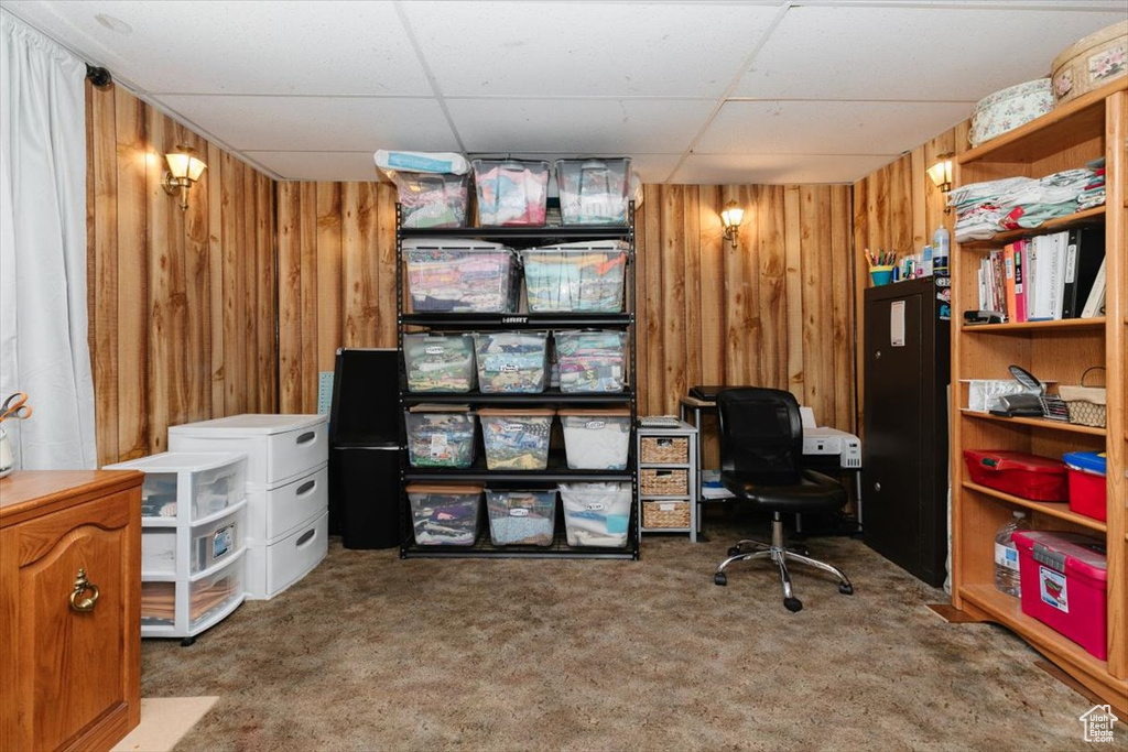 Carpeted office featuring a paneled ceiling and wood walls
