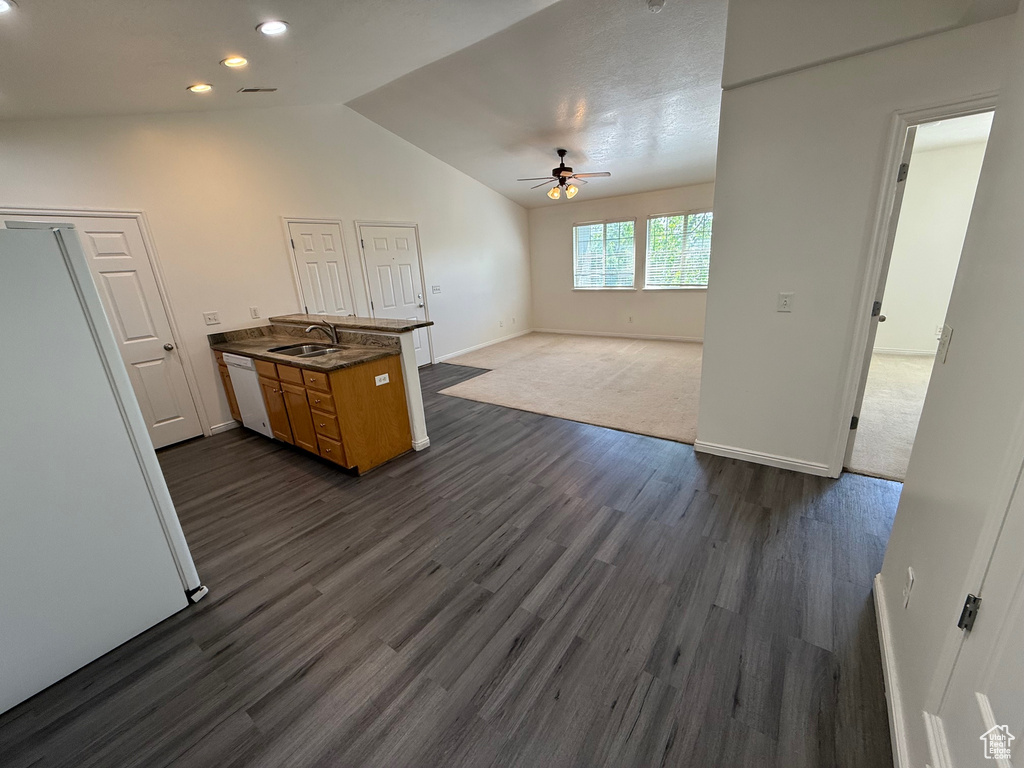 Kitchen with a ceiling fan, a peninsula, lofted ceiling, dark wood-type flooring, and white appliances