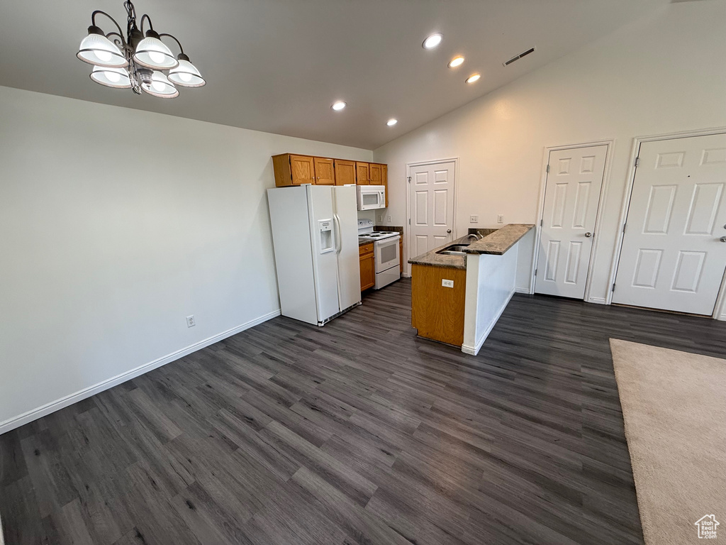 Kitchen featuring white appliances, a chandelier, lofted ceiling, recessed lighting, and dark wood finished floors
