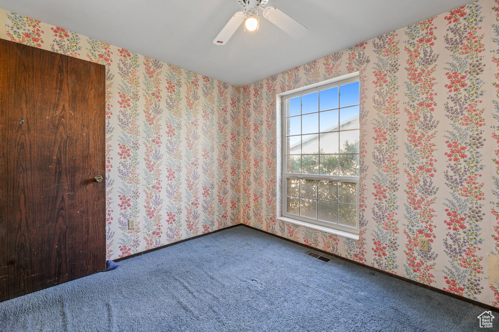 Carpeted spare room with ceiling fan and wallpapered walls