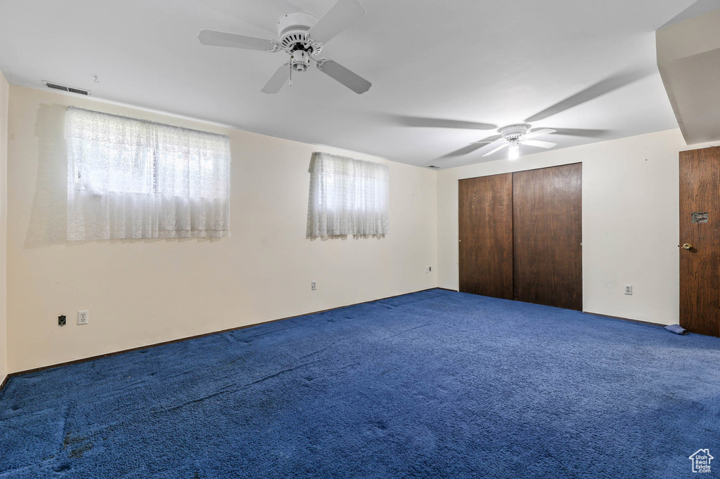 Unfurnished bedroom with multiple windows, carpet, and a ceiling fan